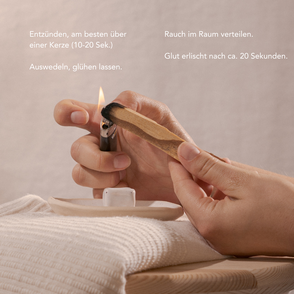 Person lighting a wooden incense palo santo with a match, on a neutral background.